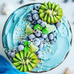 Light blue nice cream smoothie bowl topped with blueberries, kiwi, lime and mint leaves