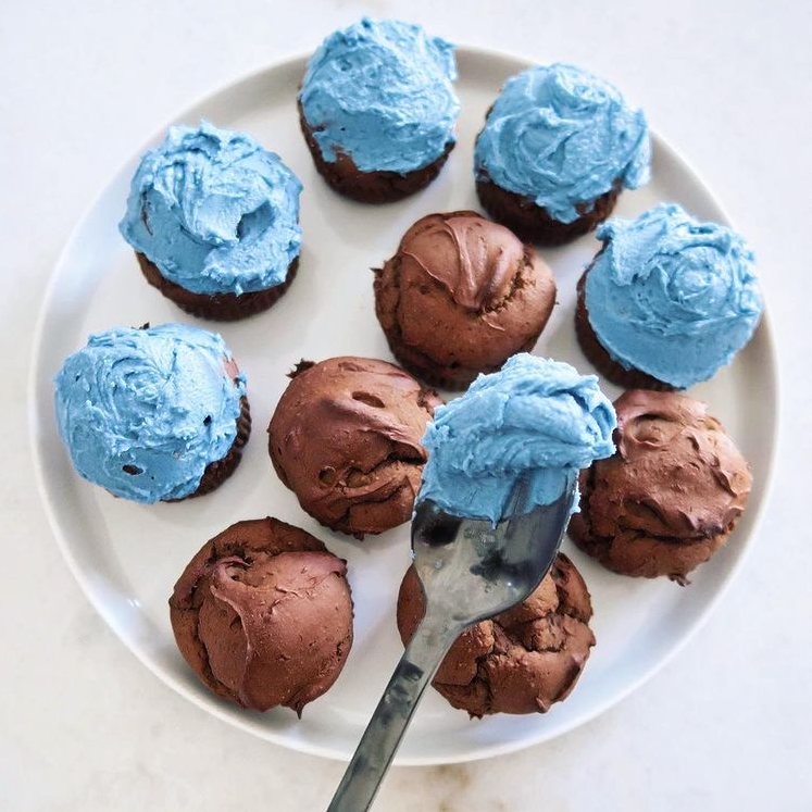 ten cupcakes with blue and brown frosting on a white plate