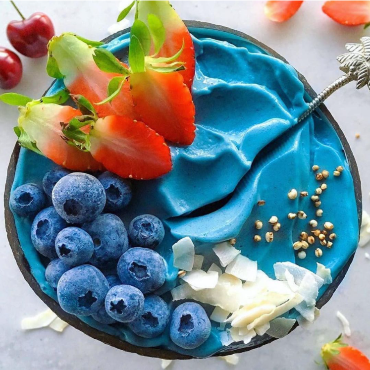 Blue smoothie bowl topped with blueberries and sliced strawberries